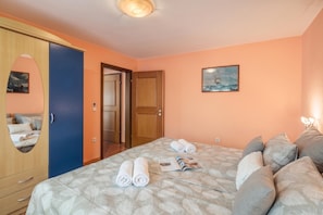 A bedroom with a bed, towels, a painting, and a wardrobe. - Magda 1 Apt with Panoramic Sea View, Plomin, Croatia (Plomin)