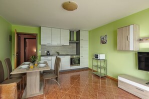 A compact kitchen with white cabinets, a microwave, and a dining area with chairs and a table set for two. - Magda 1 Apt with Panoramic Sea View, Plomin, Croatia (Plomin)