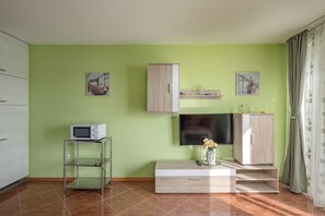 A living room with a flat-screen TV, a cabinet, a small table with a microwave, and artwork on the walls. - Magda 1 Apt with Panoramic Sea View, Plomin, Croatia (Plomin)