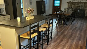 Una cocina con una isla central, piso de madera y un comedor con sillas y una mesa.