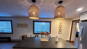 Una cocina moderna con una isla central, armarios blancos y dos lámparas colgantes.