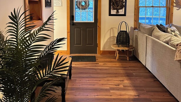 Un salón acogedor con suelo de madera, un sofá, un banco y una planta en maceta.
