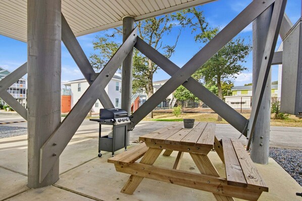 A covered outdoor area with a picnic table and a barbecue grill. - Portobello II 1316 - 2nd Row Community in Garden City Beach (Garden City Beach)