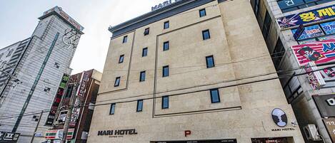 Ein Hotel mit einem gut sichtbaren Schriftzug 'MARI HOTEL', mehreren Fenstern und einem deutlichen Eingang.