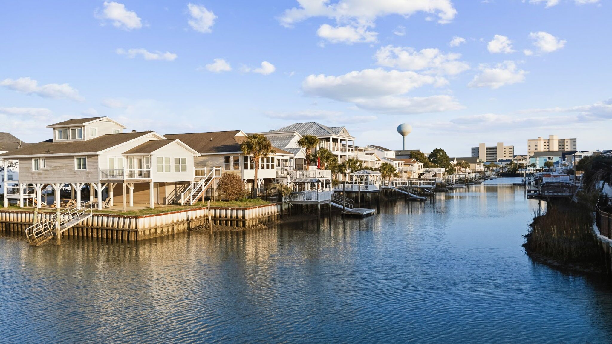 A waterfront property with multiple houses, docks, and a clear sky.
