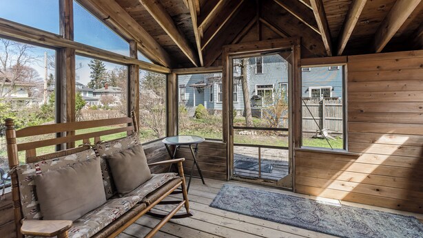 Interior de madera con un banco, una mesa y ventanas amplias que ofrecen vistas al exterior.