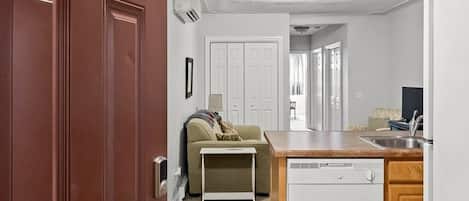 A compact kitchen with a dishwasher, a dining area with a table, and a sofa.