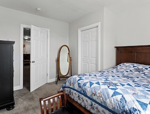 Une chambre à coucher avec un lit, une commode, un miroir et une porte.