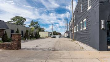 A residential street with houses, a gravel driveway, and utility poles.