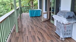 Ein überdachter Außenbereich mit Holzterrasse, einem überdachten Tisch und einem Grill.
