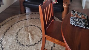 Ein Zimmer mit einer schwarzen Ledersofa, einem Holzesstisch mit einem gewebten Teppich und einem Bett mit Blumenmuster-Bettwäsche.