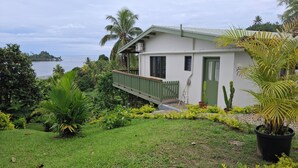 Ein Haus mit grüner Tür, einer kleinen Veranda und Blick aufs Meer.