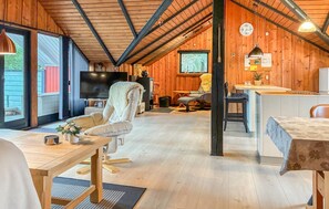 A cozy cabin interior with a wooden ceiling, a television, a dining area, and a kitchen space. - Cozy home in Toftlund with WiFi (Toftlund)