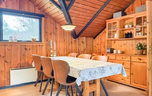 A wooden dining room with a table and chairs, a window with a view, and a cabinet with glass doors. - Cozy home in Toftlund with WiFi (Toftlund)