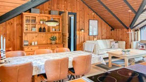 Interior acolhedor de uma cabana com área de refeições, um sofá e cozinha.