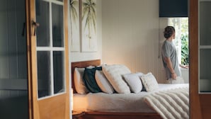 A bedroom with a wooden bed, white bedding, and a large window.