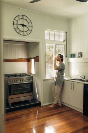 Une cuisine équipée d’une cuisinière à gaz, d’une horloge et d’une fenêtre.