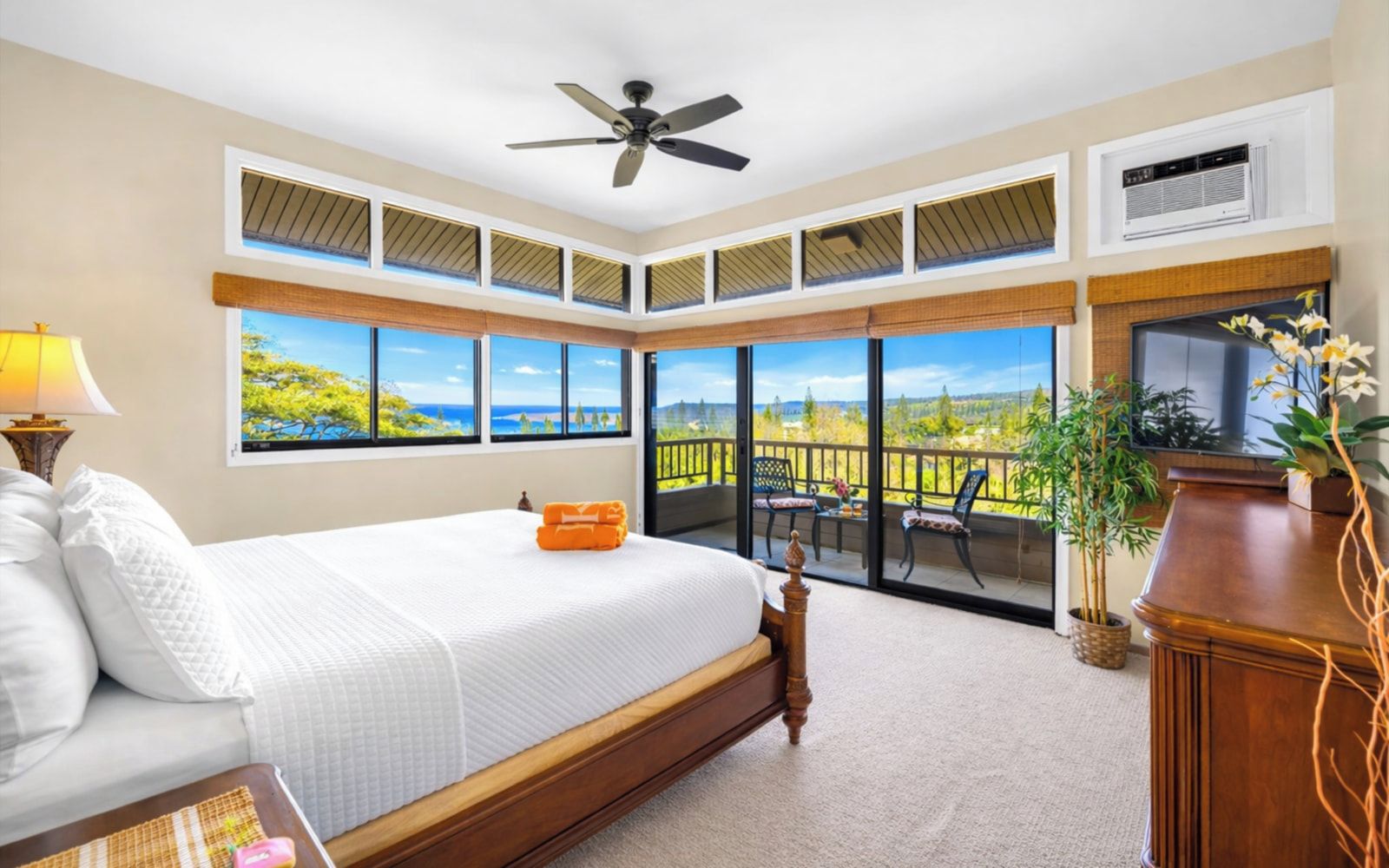 Un dormitorio con cama, ventilador de techo, televisor y balcón con vistas.