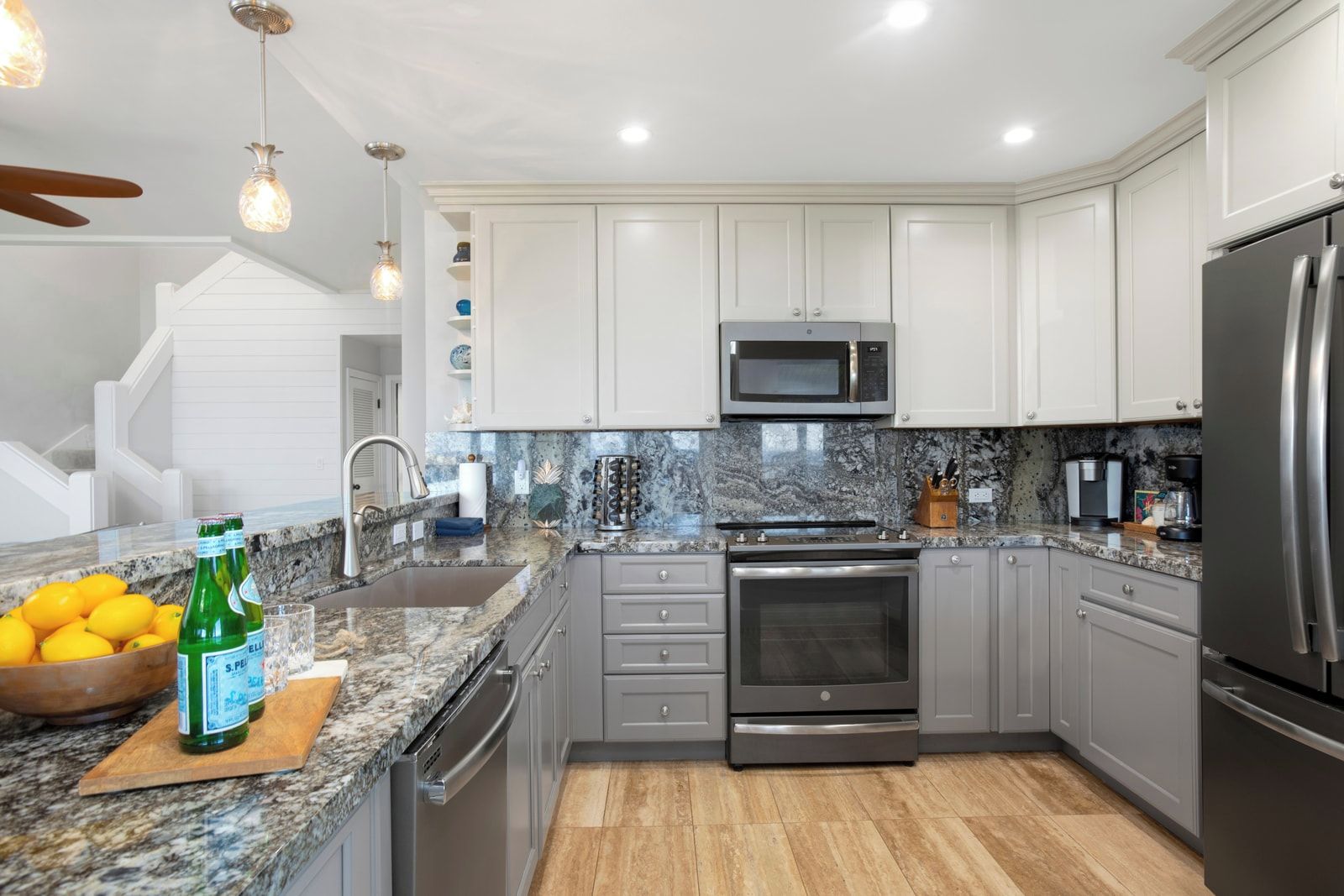 A modern kitchen with white cabinets, a stainless steel refrigerator, a microwave, and a built-in oven.