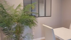 Una habitación con una mesa de comedor, sillas, una planta en maceta y una lámpara en el techo.