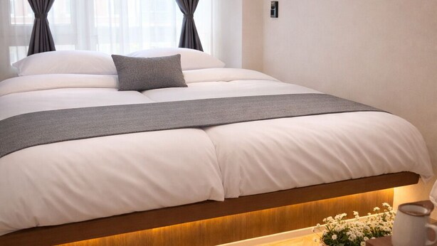 Un dormitorio moderno con una cama grande, cortinas grises y un cabecero de madera.