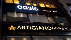Un edificio con letreros iluminados que dicen 'oasis' y 'ARTIGIANO'.