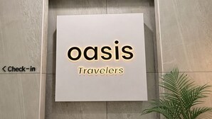 Un letrero con la palabra 'oasis' y 'Travelers' que indica una zona de recepción.