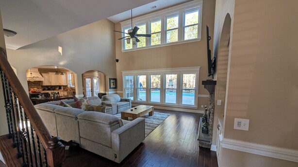 A spacious living room with a large sectional sofa, a wooden coffee table, and a view of the outside through large windows. - Stunning 4-Bedroom Retreat with Resort-Style Backyard in
 charming Evans. (Evans)
