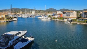 A marina with boats docked, surrounded by buildings and hills in the background. - Beautiful 2-room apartment with Wi-Fi and mooring – View over the canals of Port Grimaud (PORT GRIMAUD)