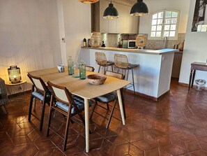 Ein Essbereich mit Holztisch und -stühlen, im Hintergrund eine Küche und ein Fenster mit Blick.