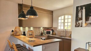 Una cocina moderna con una isla de madera, dos lámparas colgantes, un microondas y un fregadero.