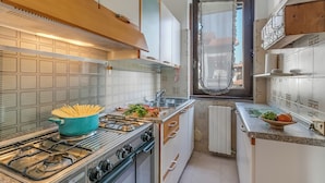 Eine kleine Küche mit einem Gaskochfeld, einem Topf Pasta und einem Fenster mit Ausblick.