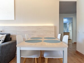 Un comedor moderno con una mesa de madera, cuatro sillas y un cabecero de color claro.