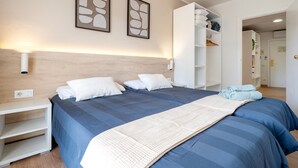 Une chambre à coucher comprenant un lit, une table de chevet, une armoire et deux œuvres d’art accrochées au mur.