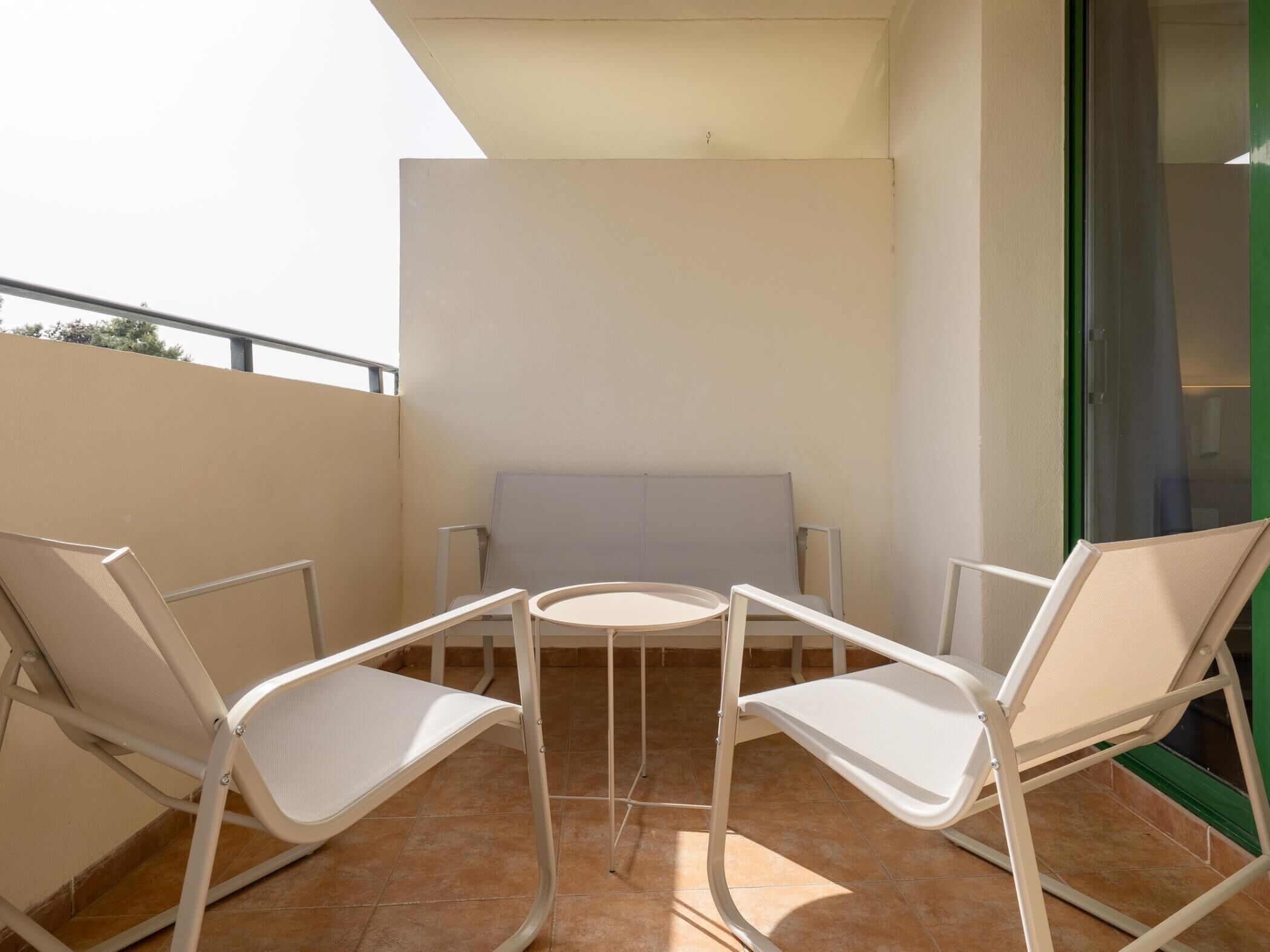 A balcony with two white chairs and a small round table.