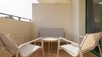A balcony with two white chairs and a small round table.