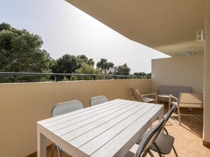 A balcony with a table and chairs, a railing, and a view of trees. - Apartment with pine forest views 800m beach (Salou)