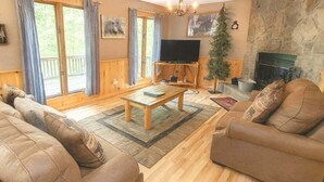 A cozy living room with a wooden floor, a sofa set, a coffee table, a television, and a fireplace. - Wandering Bear Lodge: Free Tickets /Hot Tub/ Wifi /pool table (Sevierville)