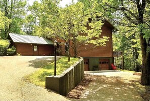 A cabin with a metal roof, surrounded by trees and a gravel driveway. - Wandering Bear Lodge: Free Tickets /Hot Tub/ Wifi /pool table (Sevierville)