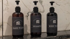 Trois bouteilles de produits ampm sur un comptoir en marbre.
