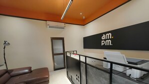 Un espace d’accueil avec un comptoir noir, un canapé en cuir marron et une porte donnant sur une autre pièce.