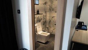 Une salle de bain équipée de toilettes, d’une douche et d’une machine à café posée sur un plateau.