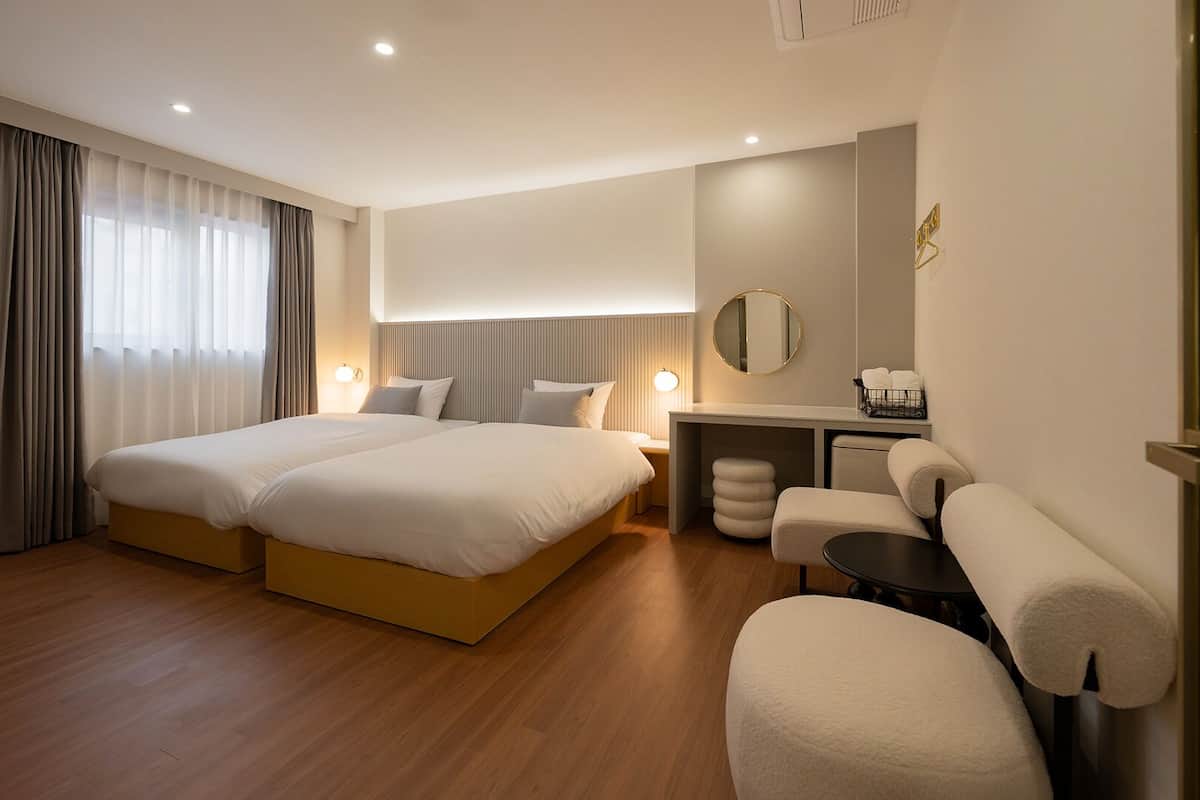 A hotel room with a double bed, a desk, a chair, and a small table.