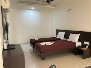Una camera d'albergo con un letto, comodini, una scrivania, una sedia e una ventola a soffitto.