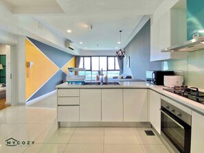 A modern kitchen with a central island, white cabinetry, and a view of the outdoors through large windows.