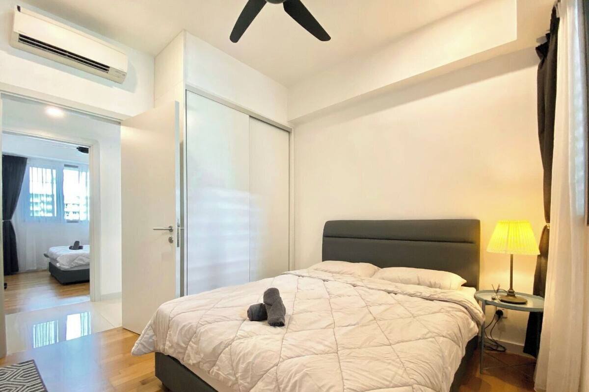 Une chambre à coucher comprenant un lit, une table de chevet, une lampe et un appareil de climatisation.