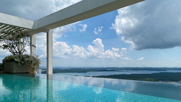 Una piscina infinita con vistas despejadas a un horizonte urbano y un cuerpo de agua.