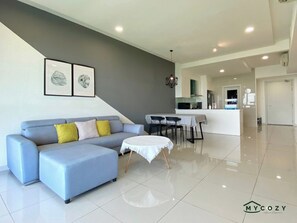 A modern living room with a sofa, a round coffee table, and a dining area with a table and chairs.