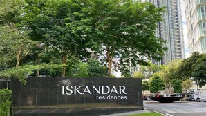 Señal de Iskandar Residences con un edificio moderno al fondo.