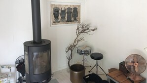 Ein Zimmer mit Kaminofen, Schlagzeug, Ventilator und einem gerahmten Kunstwerk an der Wand.